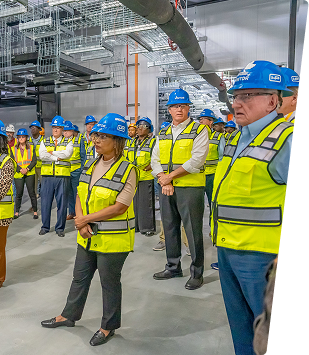 Group of professionals in safety gear touring an industrial facility.