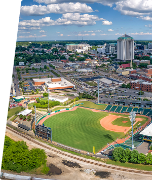 Aerial view of Montgomery with baseball stadium and cityscape under blue sky.