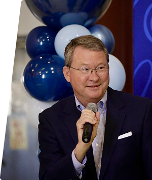 Business professional speaking at a regional event with balloons in the background.