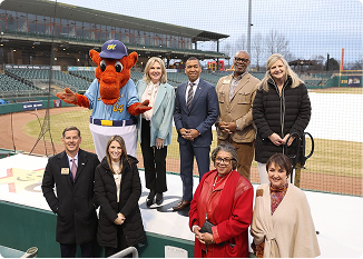 Group of diverse professionals and mascot at a baseball stadium event.