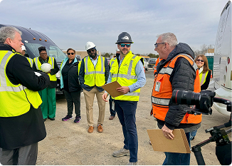 Group of professionals in safety vests discussing at construction site.
