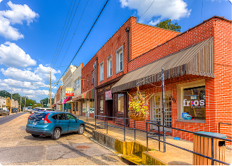 Vibrant downtown street scene in Central Alabama with shops and parked cars.