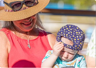 Mother and child wearing summer hats outdoors in bright sunlight.