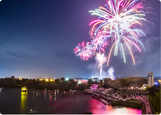 Colorful fireworks illuminate the night sky over a waterway in Central Alabama.