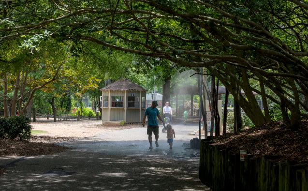 Family walking in a lush park with trees and a gazebo in Central Alabama.
