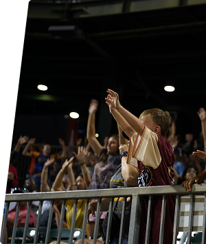 Children raising hands at a community event in an indoor venue.