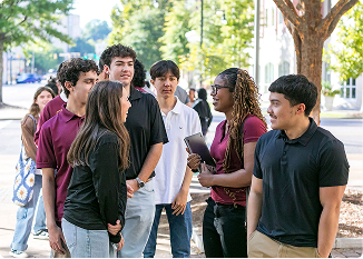 Group of diverse students talking outdoors in a park setting.