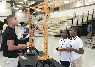 Students examining a large robotic crane at a community event in Central Alabama.