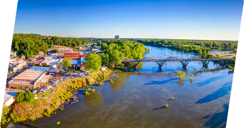 Aerial view of Central Alabama river with bridge and cityscape.